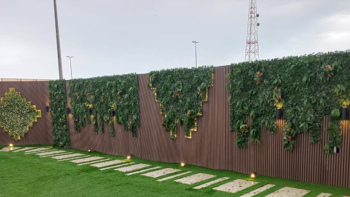 ممر بلاط وسط عشب مع جدران خضراء وإنارة في حديقة فيلا بشمال الرياض